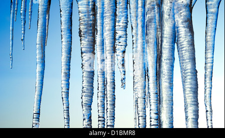 Gefrorene lange Eiszapfen auf blauen Himmelshintergrund isoliert Stockfoto