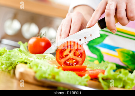 Frauenhand Tomate hinter frisches Gemüse schneiden. Stockfoto