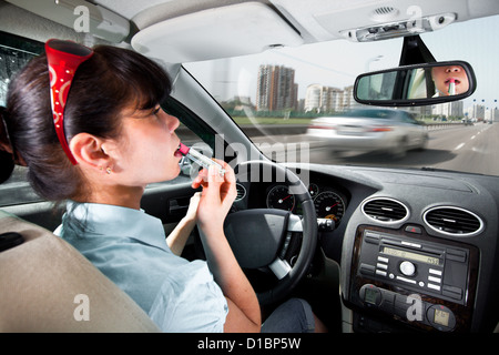 Frauen machen Lippen am Steuer des Autos Stockfoto