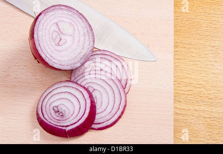 Rote Zwiebel auf Holzblock Hälfte und Scheiben mit Messer Stockfoto