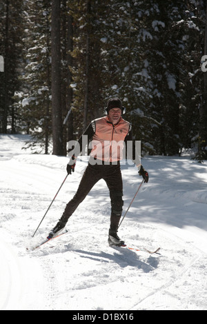 Skate-Skifahrer zoomt nach unten eine Langlauf-Loipe mit Schnee fällt um ihn herum, wie er geht. Stockfoto