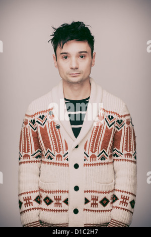 Ernster Mann in weiß, gemusterten wollene Strickjacke und Schwarzes T-shirt aus Baumwolle. Stockfoto