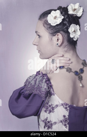 eine Frau in einem Zeitraum Kleid mit Blumen im Haar Stockfoto