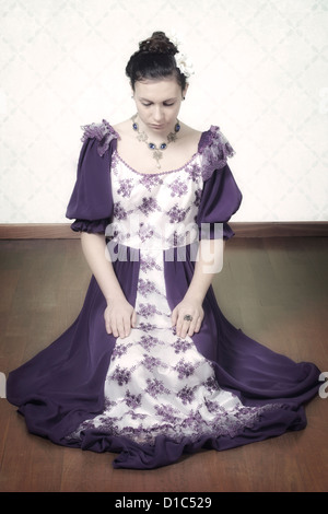 eine Frau in einem Zeitraum Kleid sitzt auf dem Boden Stockfoto