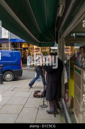 Totnes, Devon, England. 12. Dezember 2012. Busker draußen, eine Buchhandlung, die Trompete zu spielen. Stockfoto