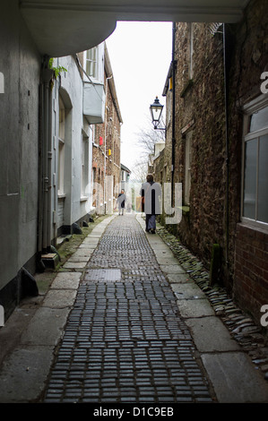 Totnes, Devon, England. 12. Dezember 2012. Gepflasterten engen Gasse mit Fußgängern und ein altes umgearbeitet Straßenlaterne. Stockfoto