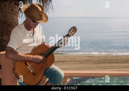 Reifer Mann, die Gitarre zu spielen, am Strand in Spanien Stockfoto