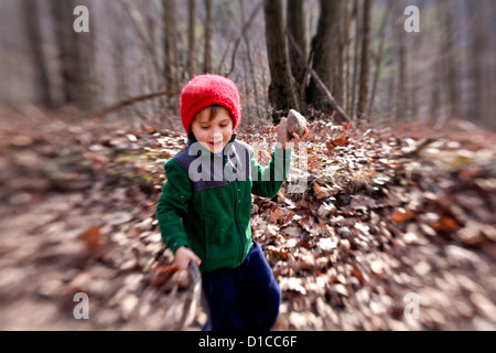 Kleiner Junge mit Vlies und roten Hut gehen auf eine Wanderung und sammeln von Feuerholz Stockfoto