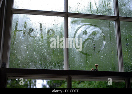 Trauriges Gesicht im Fenster Kondensation gezeichnet. Stockfoto