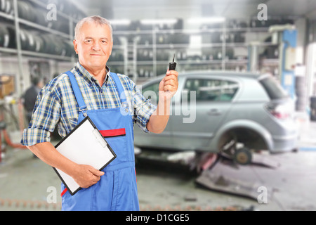 Reifen Kfz-Mechaniker mit Zwischenablage und Auto Schlüssel vor modernen Auto während Kfz-Wartung bei Autowerkstatt Stockfoto