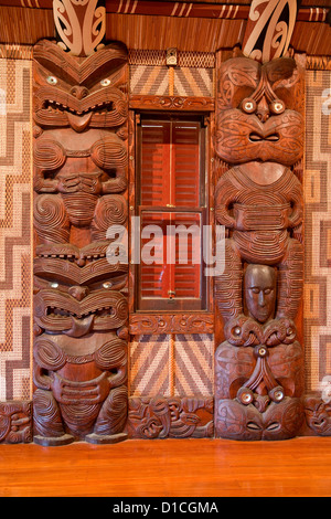 Geschnitzte traditionelle Maori Figuren, Poupou, unterstützen die obenliegenden Sparren des Haus der Begegnung, Waitangi Treaty Grounds genannt. Stockfoto