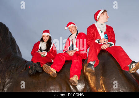 15. Dezember 2012 London UK. Schick gekleidet Nachtschwärmer sitzen auf einem Löwen Trafalgar Square Santacon 2012. Die jährliche Feier aller Dinge Weihnachten die Leute verkleidet als Weihnachtsmann als auch Elfen, Rentier und Weihnachtsbäume sieht läuft seit zwölf Jahren. Stockfoto