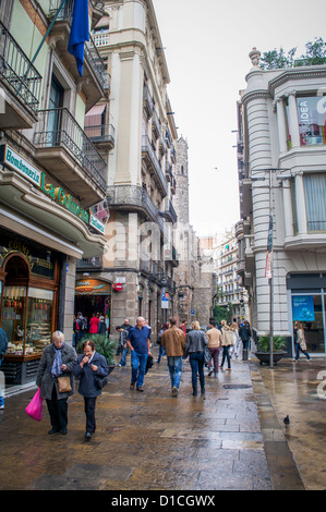 Shopping-Fans und Touristen auf den Straßen von Barcelona an einem regnerischen Sonntag Nachmittag. Stockfoto