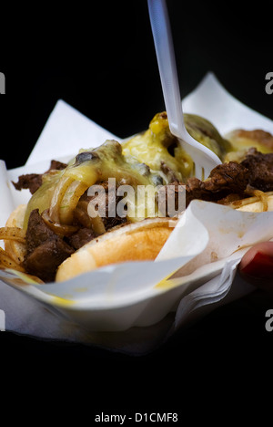 leckere Rindfleisch Fleisch Burger zum mitnehmen in eine Hand, die isoliert auf schwarz Stockfoto