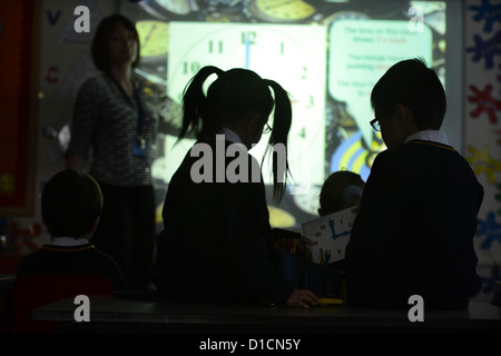 Schülerinnen und Schüler eine Lektion, die in unserer lieben Frau & St. Werburgh's katholische Grundschule in Newcastle-unter-küle Uhrablesen Stockfoto