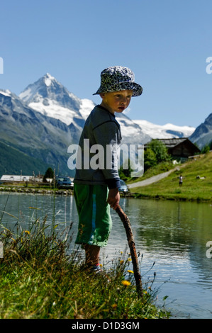 Ein Junge steht neben einer Lache des Wassers Stockfoto