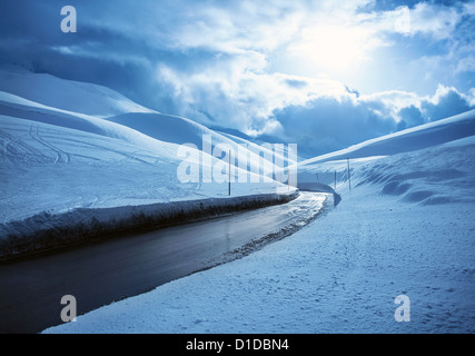 Bild der schönen verschneiten Autobahn, schwarze sauber asphaltierte Straße in Bergen bedeckt, weißen Schnee, Winter-Wetter, blaue Wolke Himmel Stockfoto