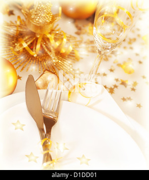 Foto von Weihnachten Tischdekoration mit goldener Dekoration und Festschmuck, Luxus weiße Platte serviert mit Silberbesteck und Weinglas Stockfoto