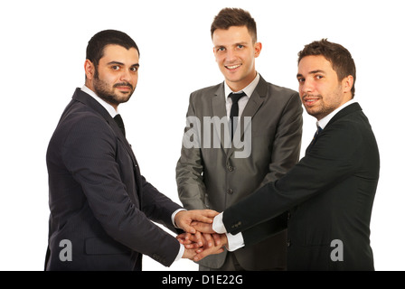 Glückliches Team der drei Geschäftsleute mit Händen an der Spitze stehen einander isoliert auf weißem Hintergrund vereint Stockfoto