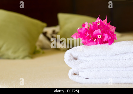 Weiße Handtücher mit Blumen auf einem Bett in einem Hotelzimmer. Selektiven Fokus auf Blumen. Stockfoto
