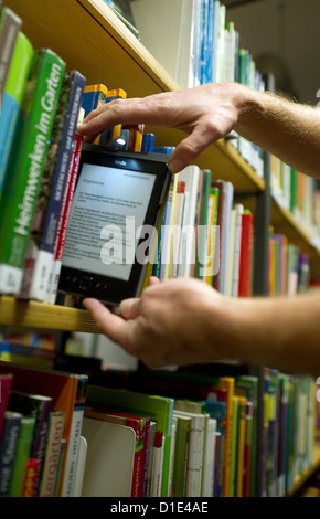 Eine Abbildung vom 4. Dezember 2012 zeigt einen Mann unter einem e-Reader von einem Bücherregal in der Zentralbibliothek in Hamburg, Deutschland. 13.000 e-Books können online ausleihen und auf e-Readern oder smart-Phones gelesen werden. Foto: Alex Ehlers Stockfoto