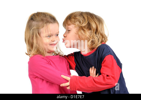 Kleiner Junge, eine Mädchen in weißen isoliert zu küssen versucht Stockfoto