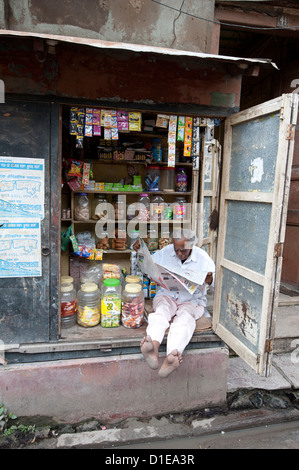 Shop-Betreiber, die Lektüre der Zeitung Morgen, Kolkata, Westbengalen, Indien, Asien Stockfoto