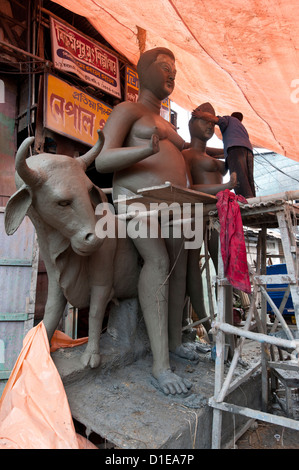 Bildhauer arbeitet an großen geformt Gottheit und Nandi den Stier, hergestellt aus Ton aus dem Fluss Hugli, Kolkata, Westbengalen, Indien Stockfoto