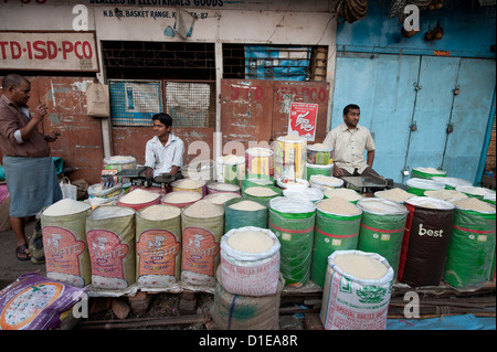 Reis vorbeilaufenden sitzt hinter Säcke Reis warten auf Kunden in den frühen Morgenstunden, neuer Markt, Kolkata, Westbengalen, Indien Stockfoto