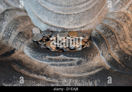 Es ist ein Foto von Close up auf Münzen, die auf die Hände der Statue des Buddha in einem Tempel oder Museum in China. Stockfoto