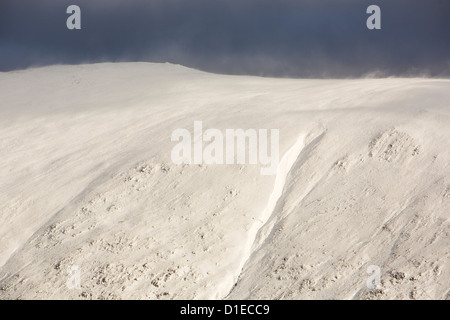 Spindrift und Schneetreiben bei starkem Wind auf taube Crag, Fairfield, Lake District, England. Stockfoto