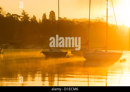 Segelboote am Lake Windermere am Waterhead, Ambleside, Seenplatte, bei Sonnenaufgang, UK, mit Willen o wisp Nebel. Stockfoto