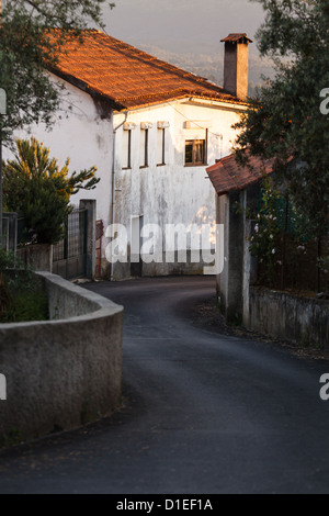 Eine schmale Straße führt vorbei an weißem Stuckhaus in die Stadt in den Bergen der Serra de Estrala Portugal Stockfoto