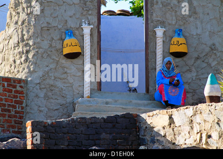 Frau sitzt in der Tür von einem Nubischen Haus in der Nähe von Assuan, Ägypten Stockfoto