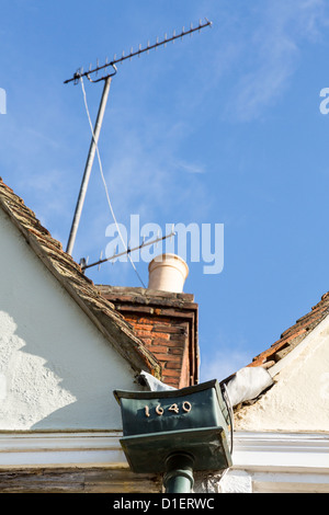 Kontrast von alt und neu mit TV Antenne und alten Blei Dachrinne Fallrohr am Dach des Hauses Stockfoto