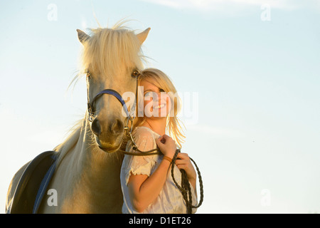 Lächelnde Frau in weißem Kleid mit Pferd, Porträt Stockfoto