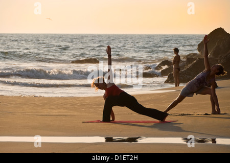 Horizontale Porträt von Frauen, die Yoga am Strand bei Sonnenuntergang in Varkala, Kerala. Stockfoto