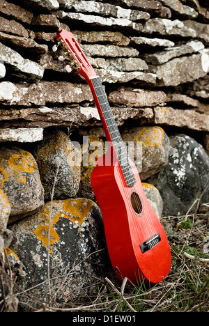 Rote Gitarre außerhalb gegen mittelalterliche Steinmauer Stockfoto