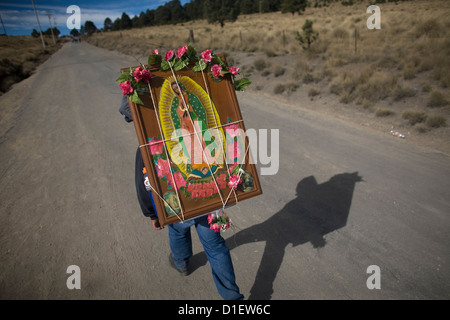 Ein Pilger tragen ein Bild der Jungfrau von Guadalupe herein eine unbefestigte Straße, wie er reist um die Basilika von Guadalupe zu erreichen Stockfoto