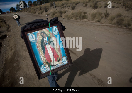 Ein Pilger tragen ein Bild der Jungfrau von Guadalupe führt durch ein Feld wie er reist um die Basilika von Guadalupe zu erreichen Stockfoto