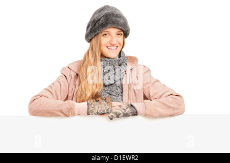 Eine lächelnde junge Frau posiert hinter einer weißen Blende Stockfoto