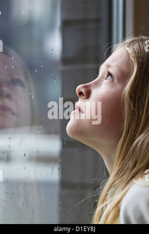 Blonde Mädchen aus verregneten Fenster Stockfoto