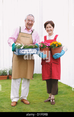 Senior paar Blumentöpfe halten und Lächeln im Garten Stockfoto