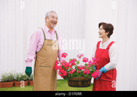 Senior paar holding Blumentopf und lächelnd in den Garten Stockfoto