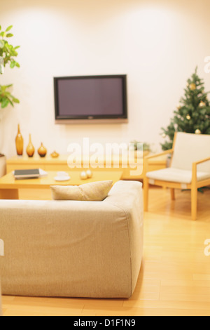 Wohnzimmer mit Möbeln, LCD-TV an der Wand und ein Weihnachtsbaum im Hintergrund Stockfoto