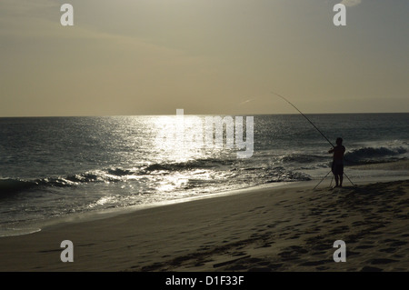 Fischer wirft eine Linie vom Strand ins Meer in der Abenddämmerung, Praia de Locacao Strand Boa Vista Kapverdische Inseln. Stockfoto