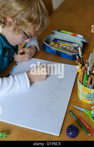 Ein kleiner Junge ist eine Liste von wünschen für Weihnachten schreiben. Stockfoto
