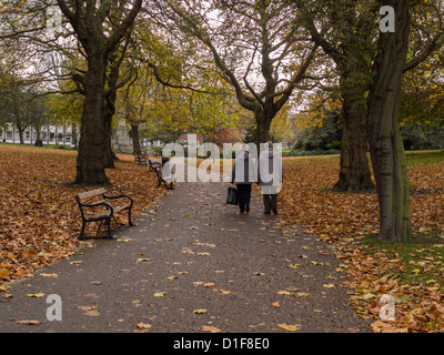 Mann und Frau, die Hand in Hand zu Fuß auf einem grünen Wanderweg in einer Parklandschaft mit Bäumen und Laub Sheffield UK Stockfoto