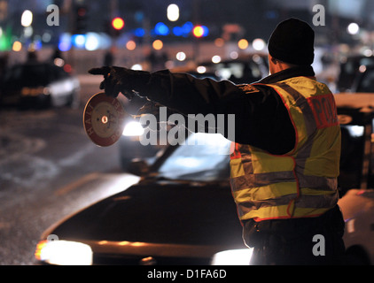 Ein Polizist zeigt ein Fahrer im Stau auf dem Alexanderplatz-Platz in Berlin, Deutschland, 14. Dezember 2012 überstreifen. Berliner Polizei intensiviert ihre Stop-und-Suche Vorgänge zu prüfen, ob Autos mit Winterreifen und möglichen Alkoholkonsum der Fahrer verlassen ein Weihnachtsfest sind Mitarbeiter, Partei oder Weihnachtsmärkte. Foto: Paul Zinken Stockfoto