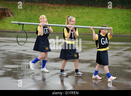 Schülerinnen und Schüler tragen ein Korbball-Ziel in unserer lieben Frau & St. Werburgh's katholische Grundschule in Newcastle-under-Lyme, Staffordshi Stockfoto